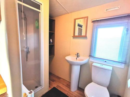 y baño con aseo, lavabo y ducha. en Charming Static Caravan, en Dawlish Warren