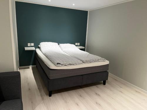 a bed in a bedroom with a blue wall at Koselig kjellerleilighet sentralt på Orkanger in Orkanger
