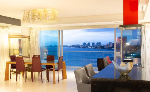 a dining room with a table and chairs and a large window at Luxury Condo Peninsula in Puerto Vallarta