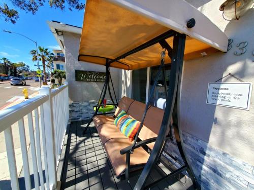 a porch swing with a bench on the side of a building at Beach-2-Bay 1br - In the Heart of Mission Beach in San Diego
