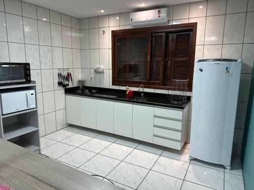 a white kitchen with a sink and a microwave at Casa Liberdade in Novo Hamburgo