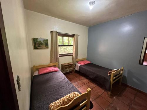 two beds in a room with a window at Casa Chalé Chácara Caminho do Vale in Nova Friburgo