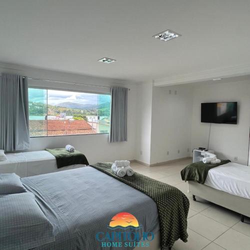 a bedroom with two beds and a flat screen tv at Capitólio Home Suítes in Capitólio