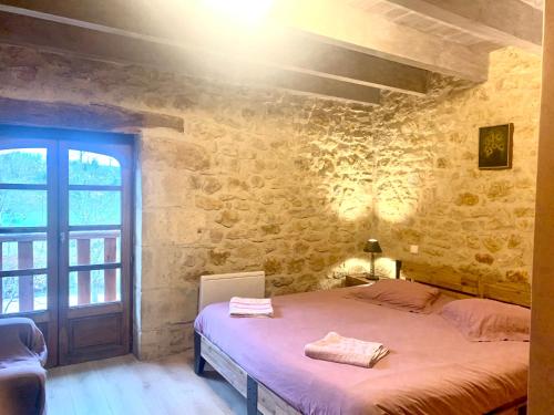 a bedroom with a bed in a stone wall at La Riviere Esperance in Veyrignac