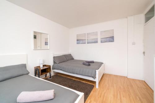 a white bedroom with two beds and a table at Spacious 1 Bed Flat in Dalston in London