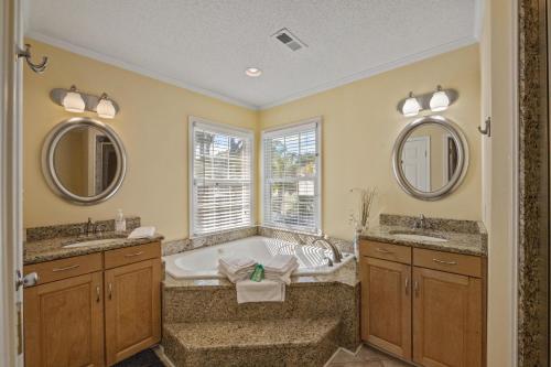 a bathroom with two sinks and a tub with two mirrors at Beaching On The Dunes - 3rd Row - Windy Hill Section in Myrtle Beach