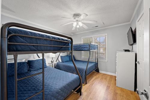 a bedroom with two bunk beds and a ceiling fan at Beaching On The Dunes - 3rd Row - Windy Hill Section in Myrtle Beach