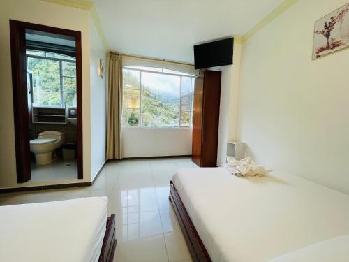 a bedroom with two beds and a bathroom with a toilet at Hostal Balcon del Cielo in Baños