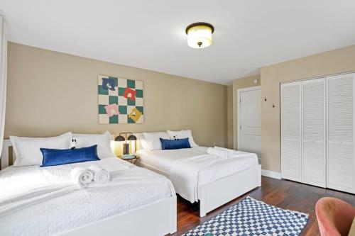 two white beds in a room with blue pillows at Housepitality - The Columbus Game House - 2 BR in Columbus