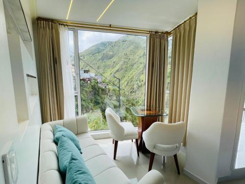 a living room with a white couch and a large window at Hostal Balcon del Cielo in Baños