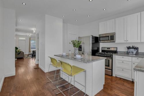 a kitchen with white cabinets and yellow bar stools at Housepitality - The Columbus Game House - 2 BR in Columbus