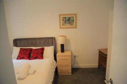 a bedroom with a bed and a lamp on a night stand at Beautiful New family home in Cross Gates