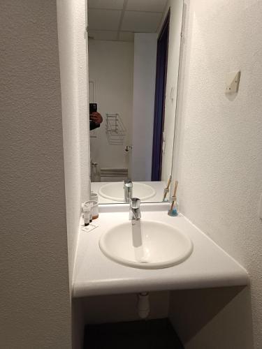 une salle de bain avec un lavabo blanc et un miroir dans l'établissement Studio proche gare avec parking, à Lourdes