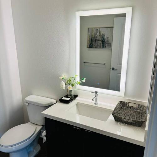 a bathroom with a toilet and a sink with a mirror at Luxury Condo with Pool & Gym ! in Glendale