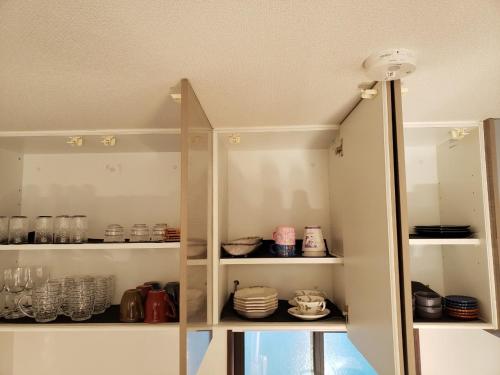 a cabinet filled with dishes and cups and plates at 一棟貸しnuevoL7～暮らすように泊まる北群馬の冒険はここから in Numata