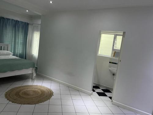 Schlafzimmer mit einem Bett, einem Fenster und einem Teppich in der Unterkunft Cavendish Suite Bachelor in Kapstadt