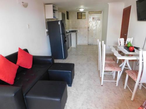a living room with a black couch and a kitchen at El Velero Apartamentos By DANP in Santa Marta