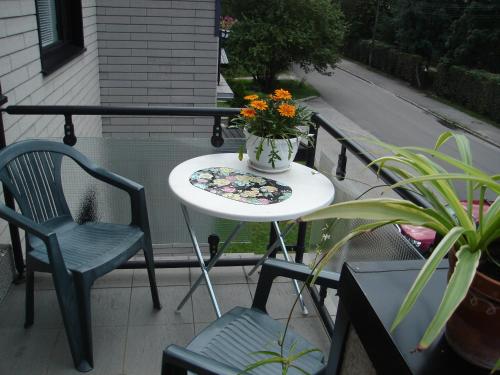a table and chairs on a balcony with a vase of flowers at Oasis Apartments in Pärnu