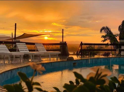 a pool with chairs and a sunset in the background at Carlo's swimming pool in Rurrenabaque