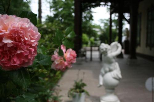 a statue of a girl next to pink flowers at Villa Musik - historical apartments, Baden in Baden