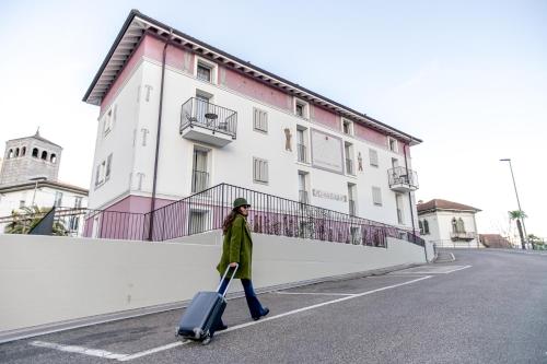 Uma mulher a andar numa rua com uma mala. em Miralago Locarno Easy Rooms em Locarno