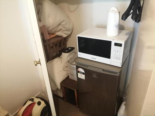 a microwave sitting on top of a refrigerator at 25 Glenfell Place - One Bedroom Studio in Auckland