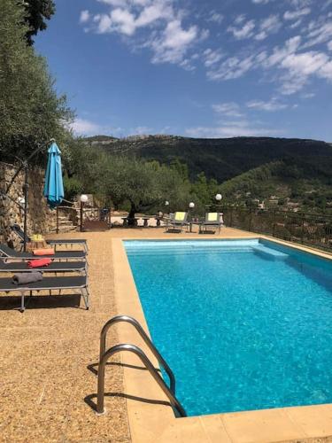 - une piscine avec 2 bancs et un parasol dans l'établissement Grande villa avec magnifique piscine et vue à couper le souffle à 20 minutes de Hyères !, à Belgentier