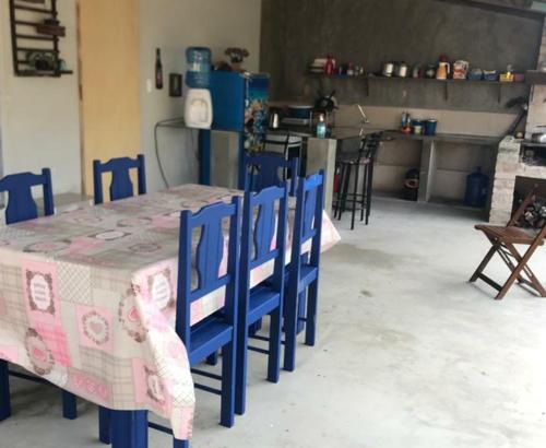 una mesa con sillas azules y un mantel rosa y blanco en Pousada Max House entre Praias de SFS, en São Francisco do Sul