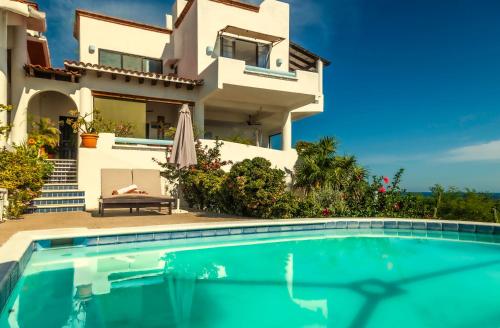a villa with a swimming pool in front of a house at Villas Mykonos in Zipolite