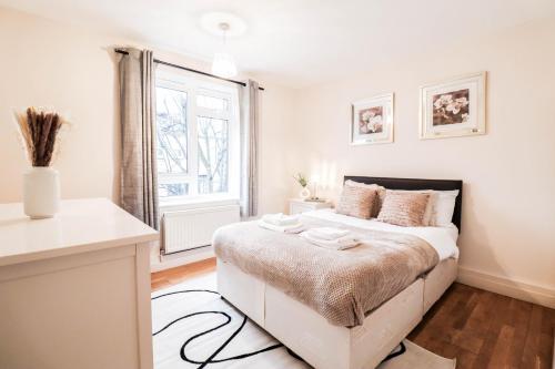 a white bedroom with a bed and a window at Fantastic 2 Bed London Apartment in London