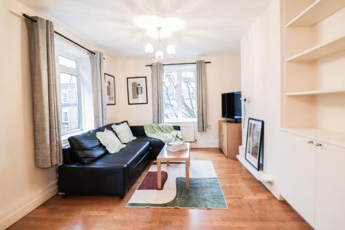 a living room with a black leather couch and a table at Fantastic 2 Bed London Apartment in London