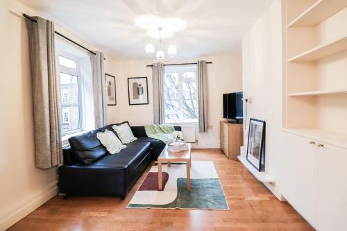 a living room with a black leather couch and a table at 2 Bed Apartment - Great Location in London