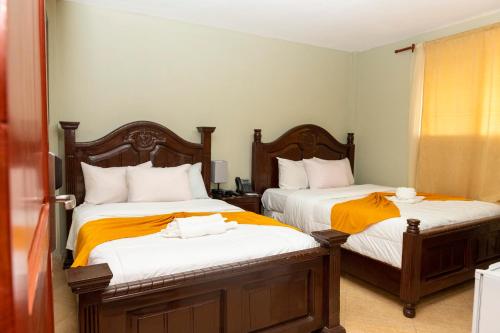 a bedroom with two beds with orange and white sheets at Vivy Hill's Hotel in Port-au-Prince