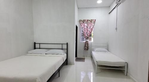 two twin beds in a room with a window at Cantik-La Homestay Kolam 6 Bilik Kuala Terengganu in Bukit Payong