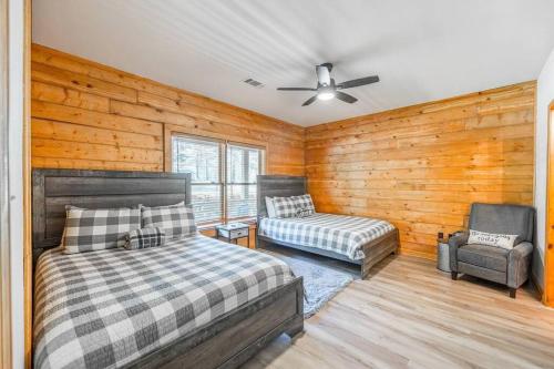 um quarto com paredes de madeira, uma cama e uma cadeira em Luxe Hot Springs Cabin w/Pond and Game Room! em Pearcy