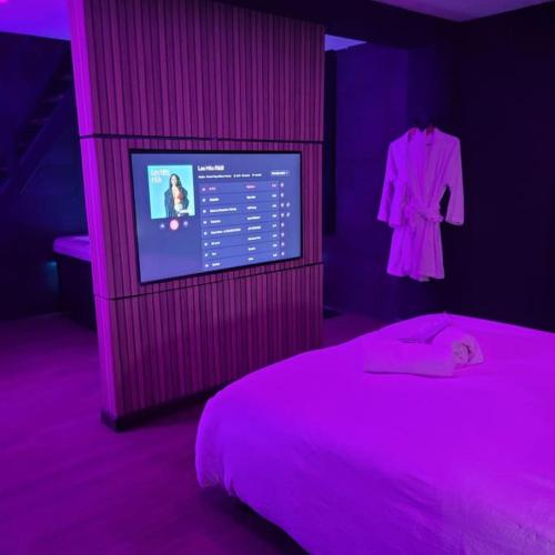 a bedroom with a bed and a dress hanging on a wall at L'Escale Suite & Spa in Therdonne