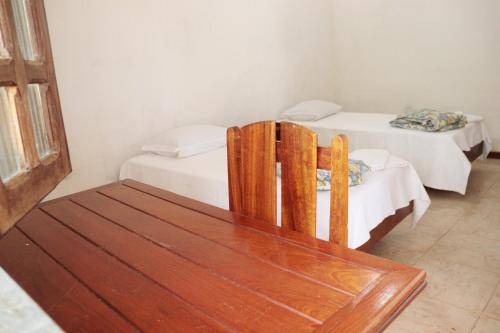 Habitación con 2 camas y silla de madera. en Hotel Estalagem Sertaneja, en Brumado