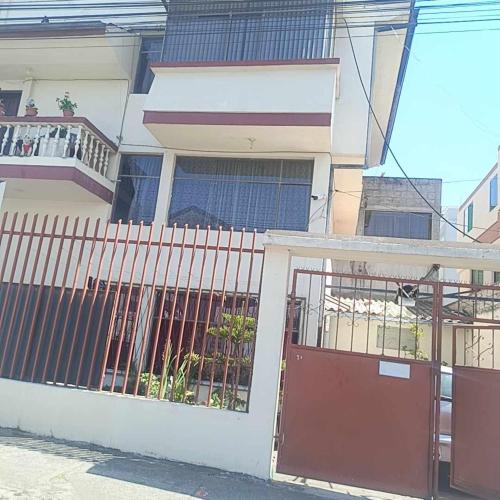 a white house with a gate and a balcony at Agradable minidepartamento central en Ambato, para una a seis personas in Ambato