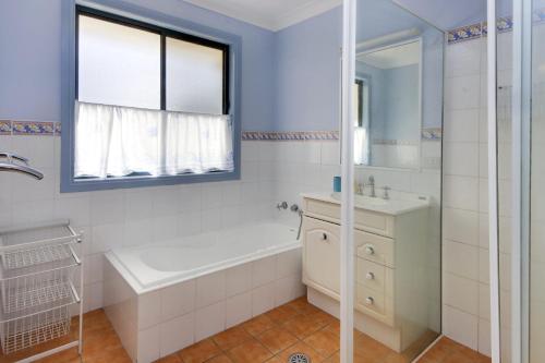 a white bathroom with a tub and a sink at Anchor Down at Hat Head - 3 Bream Close in Hat Head