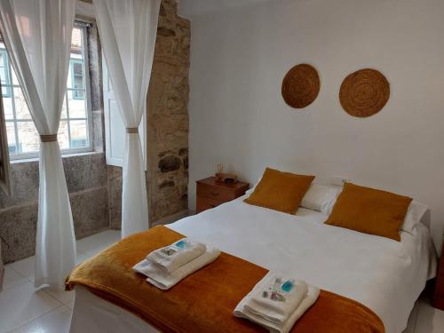una camera da letto con un letto bianco e asciugamani di A Taberna de Gundián a Vedra