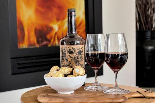 a table with two glasses of wine and a bowl of food at The Hidden Door Bowral Villa -the Love of Old Bowral in Bowral