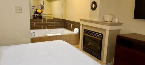 a bedroom with a fireplace and a bed and a tub at Riviera Inn And Suites 1000 Islands in Gananoque