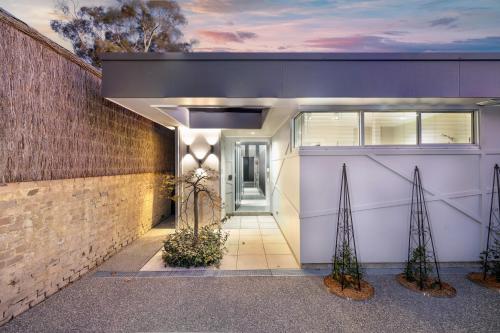 a house with a white garage with two plants at The Hidden Door Bowral Villa -the Love of Old Bowral in Bowral