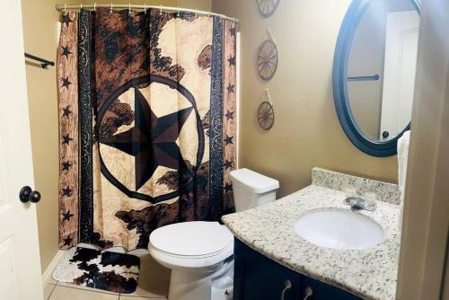 a bathroom with a toilet and a sink and a shower curtain at Western Style - 2 bed/1 bath (RATED 10 STARS) in Eagle Pass