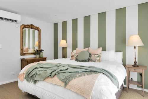 um quarto com uma cama com riscas verdes e brancas em The Hidden Door Bowral Villa -the Love of Old Bowral em Bowral