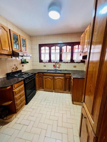 a large kitchen with wooden cabinets and black appliances at Casa andina in Esquel