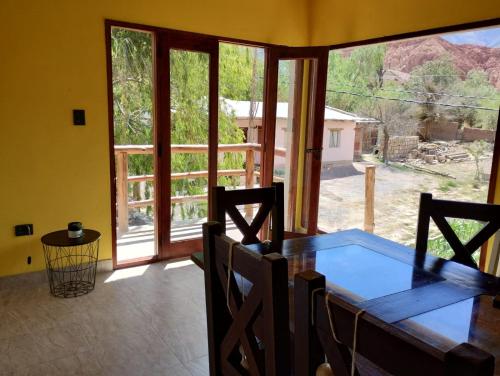 ein Esszimmer mit einem Tisch und einem großen Fenster in der Unterkunft Luna Jatun in Purmamarca