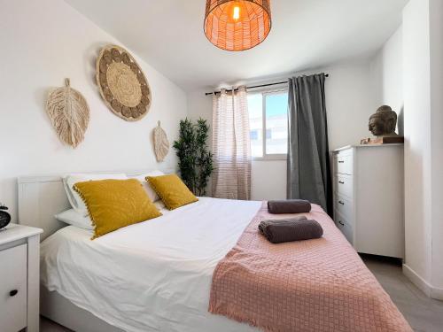 um quarto com uma grande cama branca com almofadas amarelas em Casa Sol Bristol Sunset Beach em Corralejo