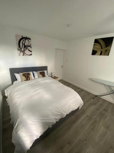 1 dormitorio con 1 cama blanca grande y suelo de madera en Chic City Retreat Immaculate 2-Bed Oasis in London, en Londres