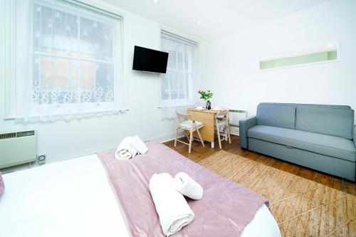 ein Schlafzimmer mit einem Bett und einem blauen Sofa in der Unterkunft Brewer Street Central Apartments in London